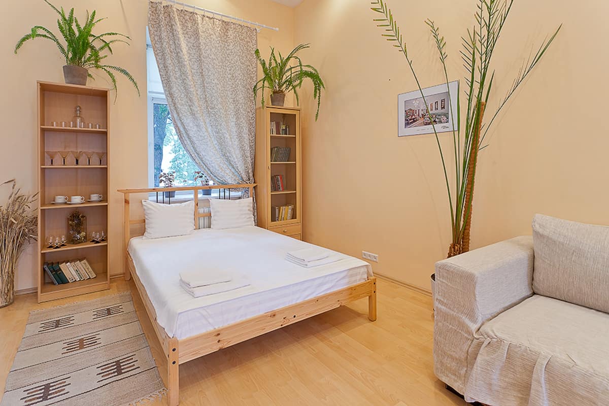 Ein Schlafzimmer mit einem hölzernen Bett, einem Sofa, einem Bücherregal und einem Blumentopf.