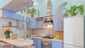 Une cuisine moderne dotée d’un îlot central, d’appareils électroménagers en acier inoxydable et de plantes en pot.