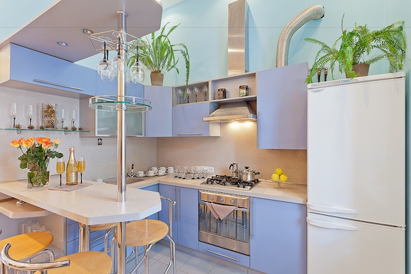 A modern kitchen with a central island, stainless steel appliances, and potted plants.