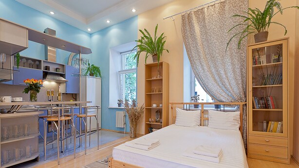 Une chambre moderne avec un lit en bois, une petite kitchenette et une bibliothèque.