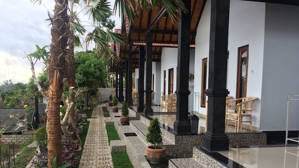 A covered outdoor area with a tiled pathway, potted plants, and outdoor seating.