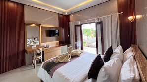 A modern hotel room with a large bed, a desk, and a television.