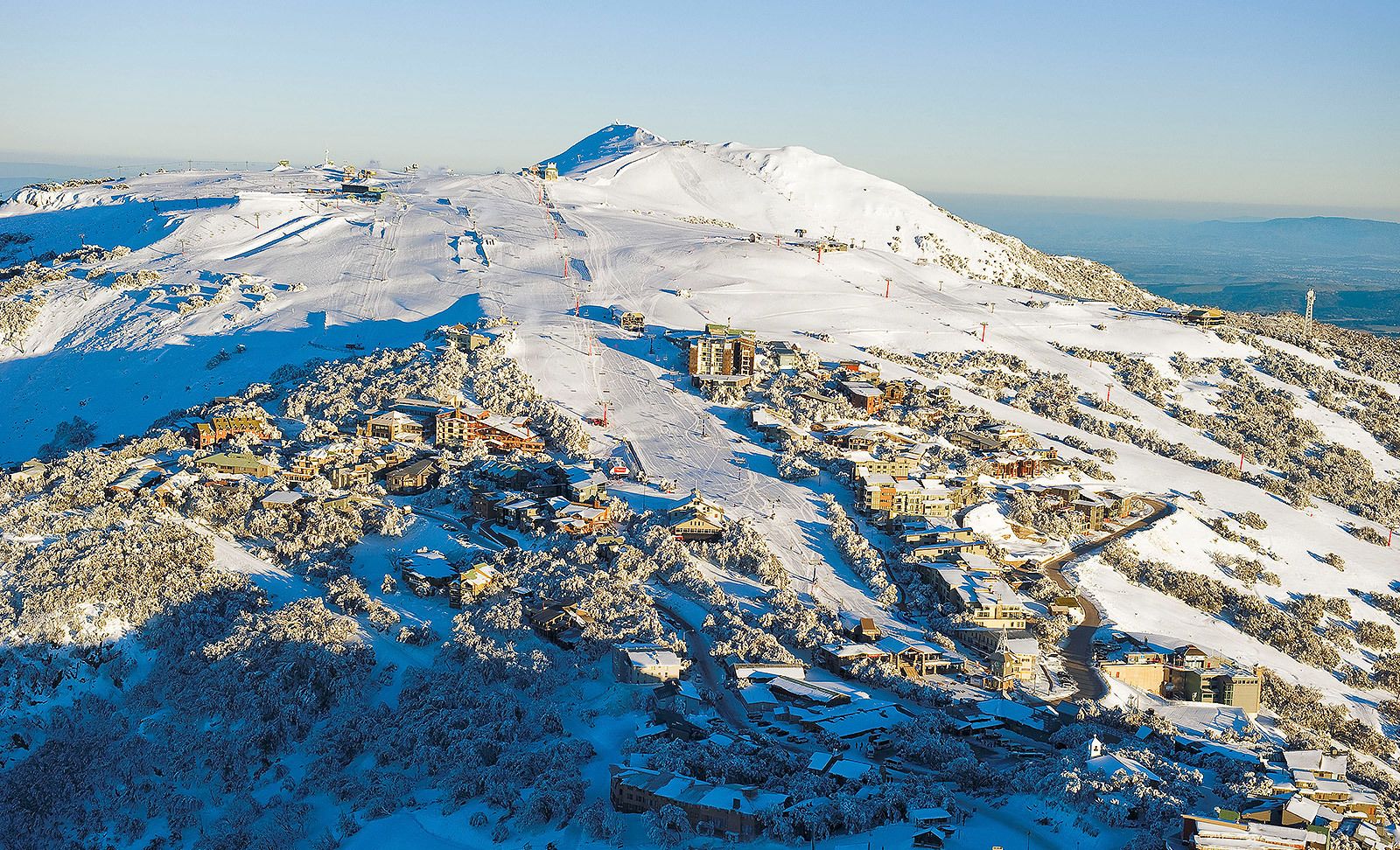 A snow-covered mountain with a ski resort, including buildings and ski slopes.