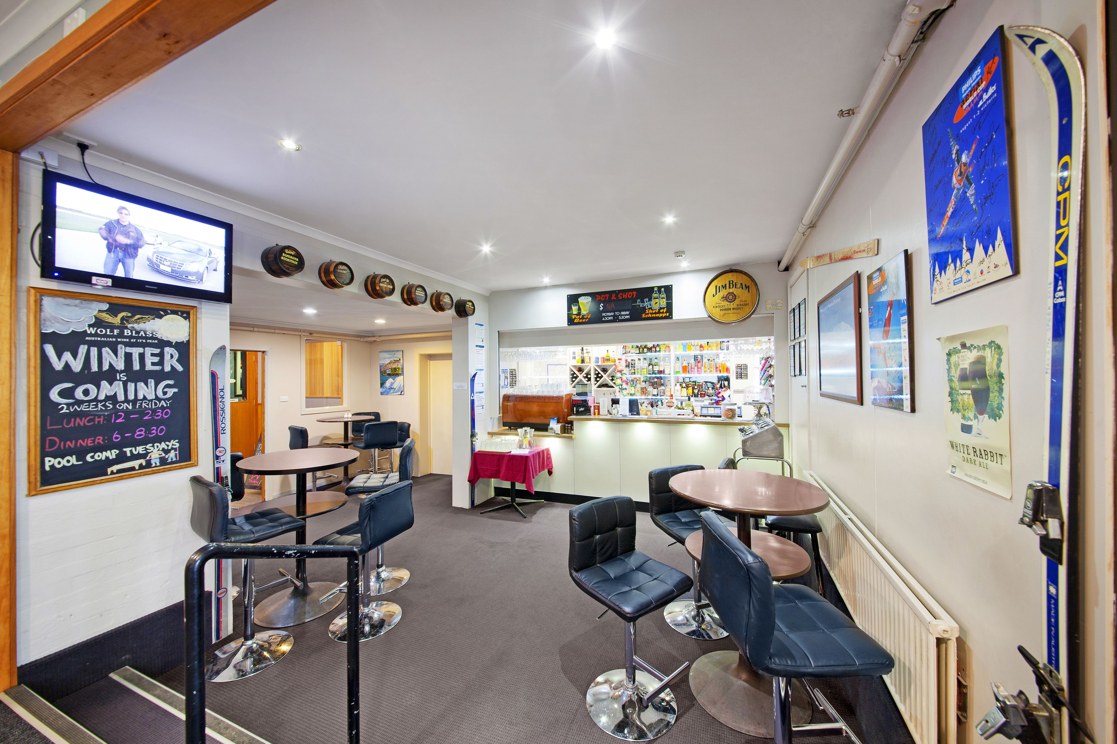 A restaurant interior with bar seating, a counter, and a menu board.
