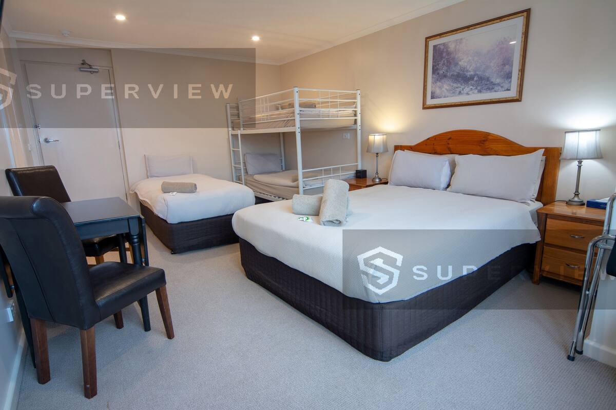 A hotel room with bunk beds, a desk, a chair, and a bedside table with lamps.
