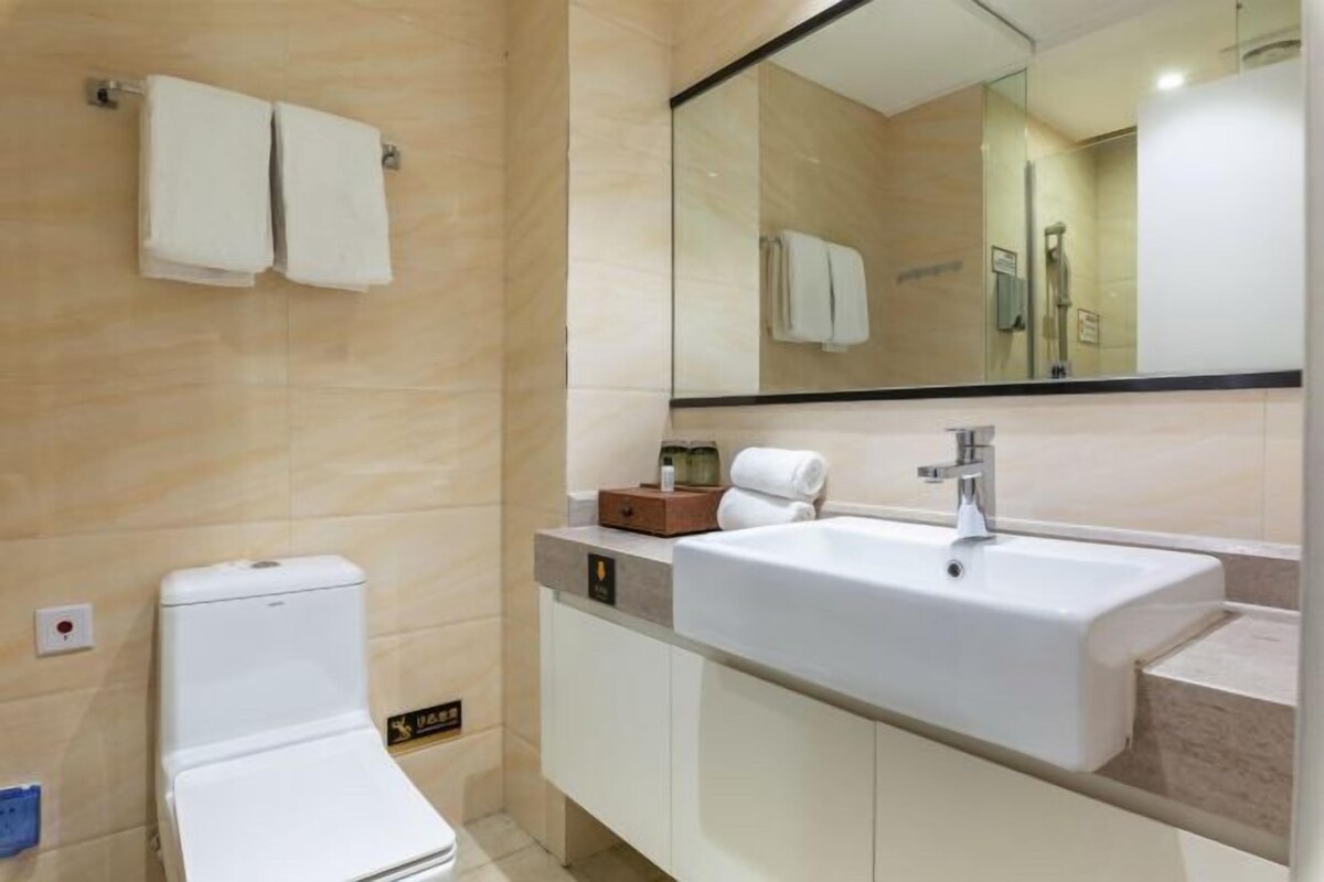 A modern bathroom with a white sink, a mirror, and a toilet.