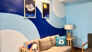 Een kamer met een bank, een lamp en twee aan de muur bevestigde afbeeldingen met ruimte thema's.