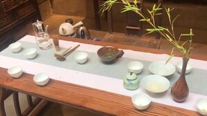 Een tafel met theeservies, kommen, een theepot en een bamboeplant.
