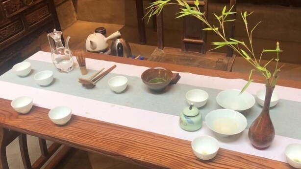 A table with various tea utensils and bowls, a teapot, and a bamboo plant. - Sun Forest Resort Hotel (Huangshan)