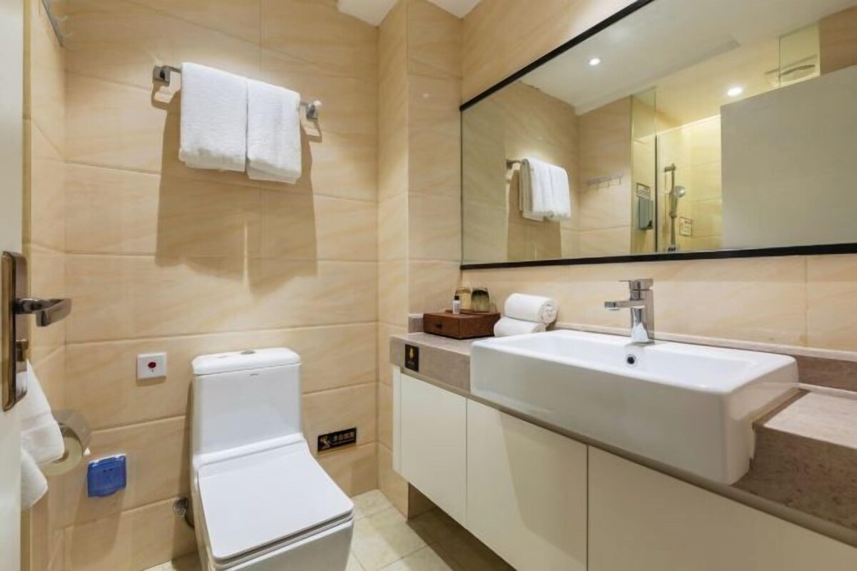 A modern bathroom with a toilet, sink, and mirror.