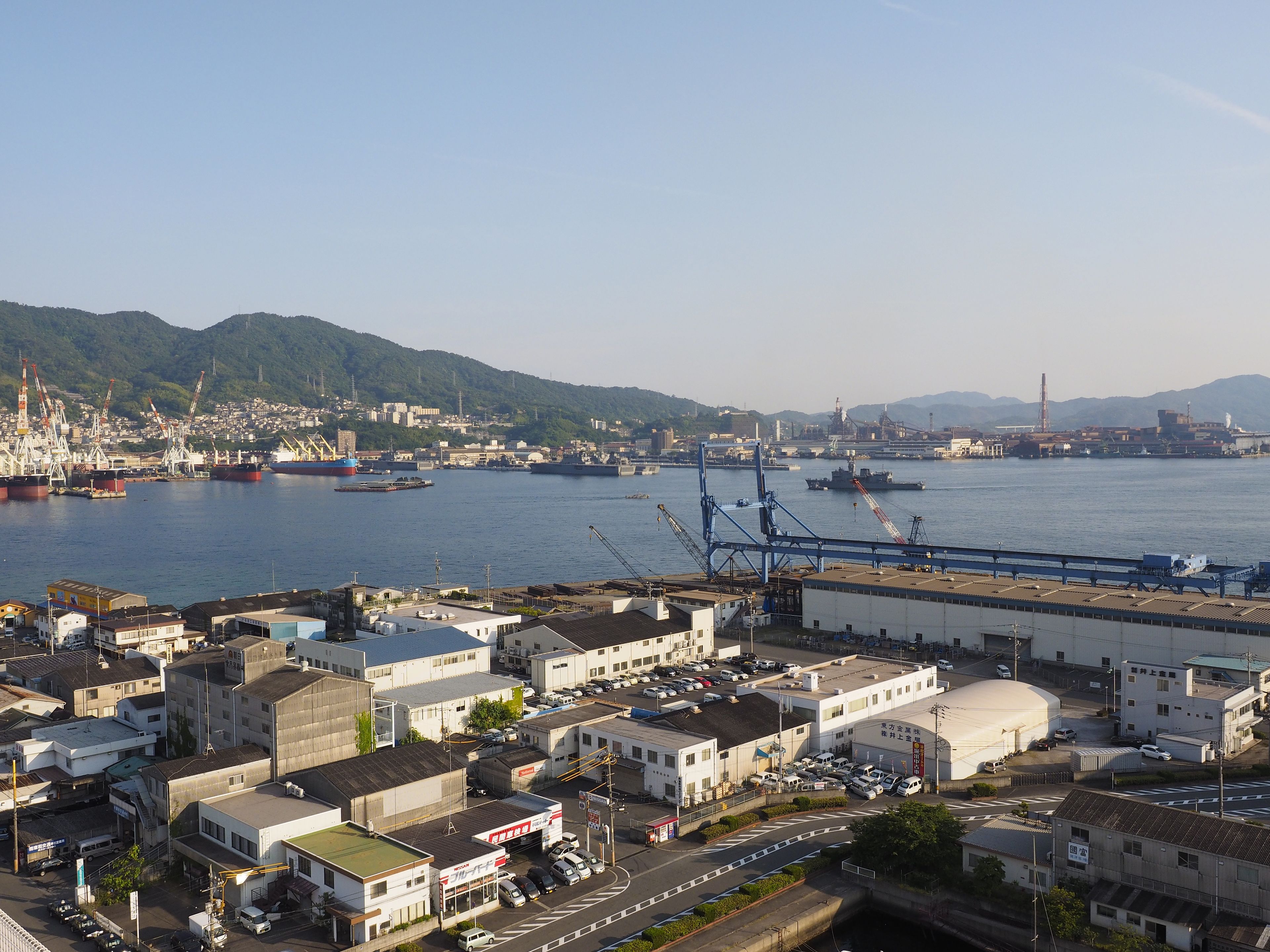 A coastal industrial area with shipping docks, cranes, and large ships.