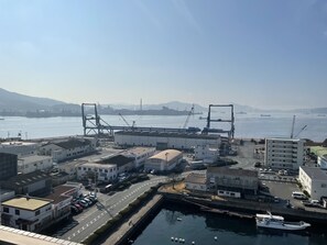 Zona costera industrial con grúas portuarias, un puerto y una carretera que conduce a edificios.