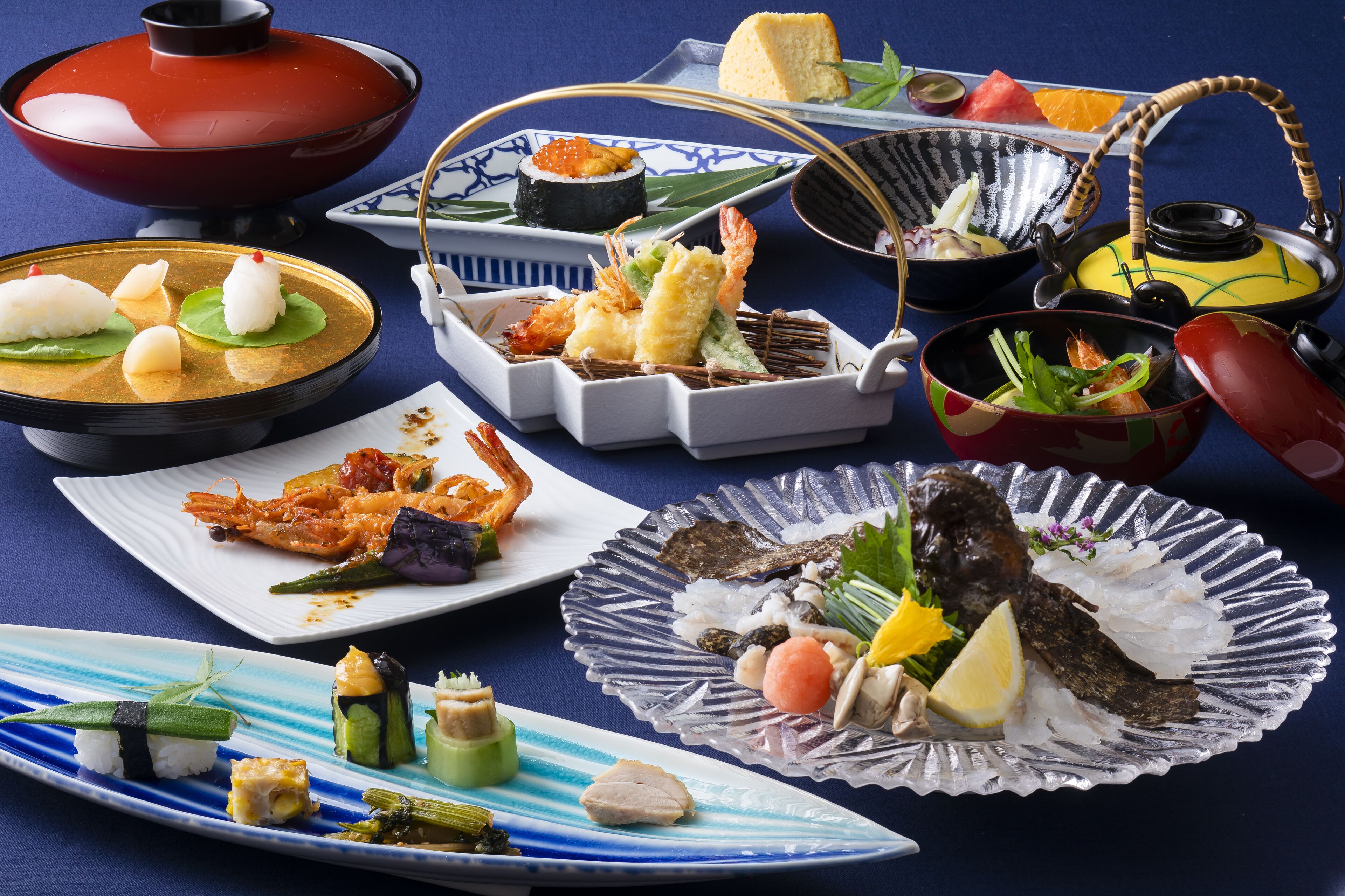 Verschiedene japanische Gerichte, darunter Sushi, Sashimi und Tempura, serviert auf traditionellem Porzellan und Glaswaren.