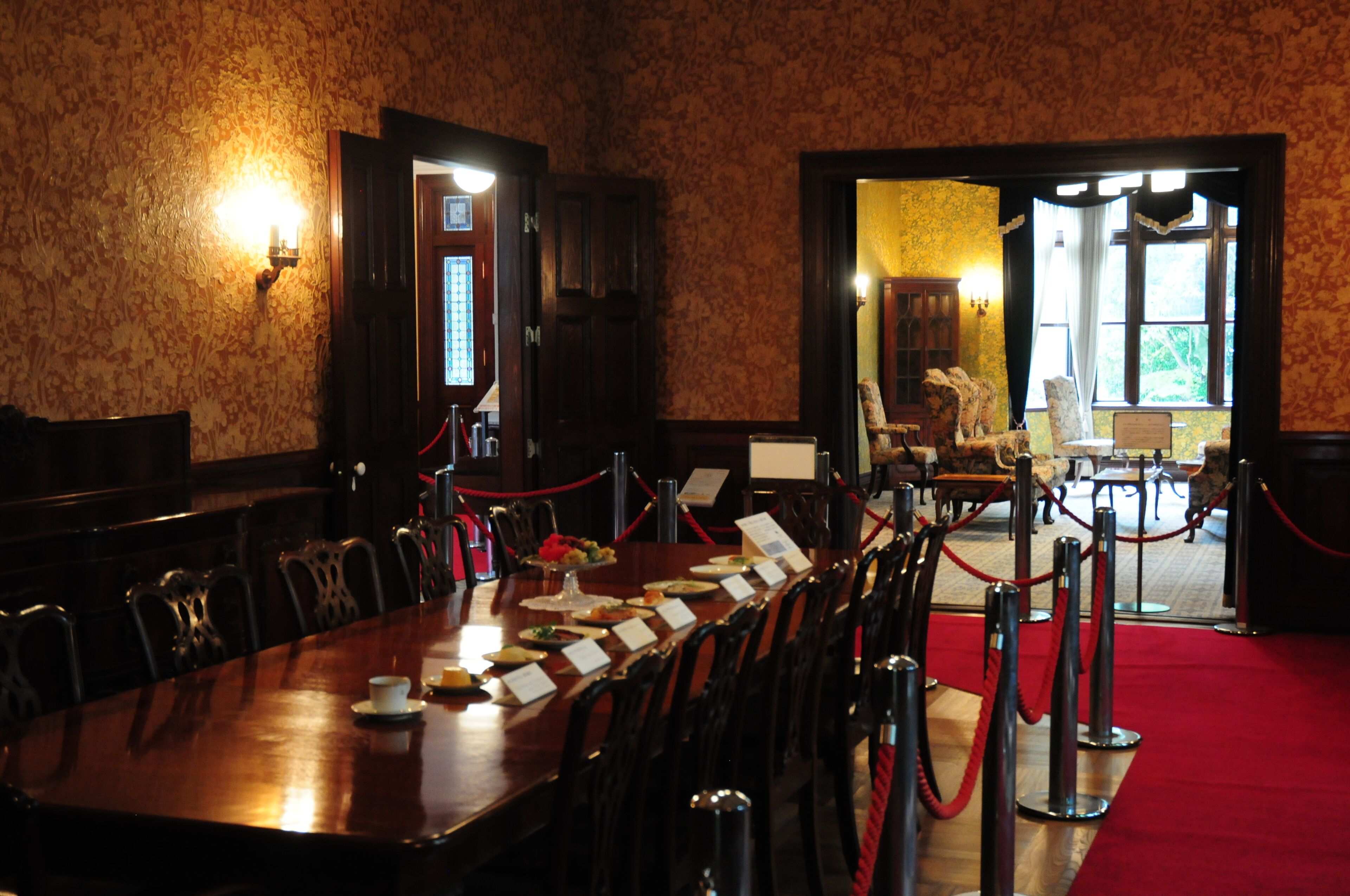 Un salón de conferencias con una mesa larga, sillas y una alfombra roja.