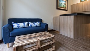Une pièce avec un canapé bleu, une table basse en bois et un tableau encadré accroché au mur.
