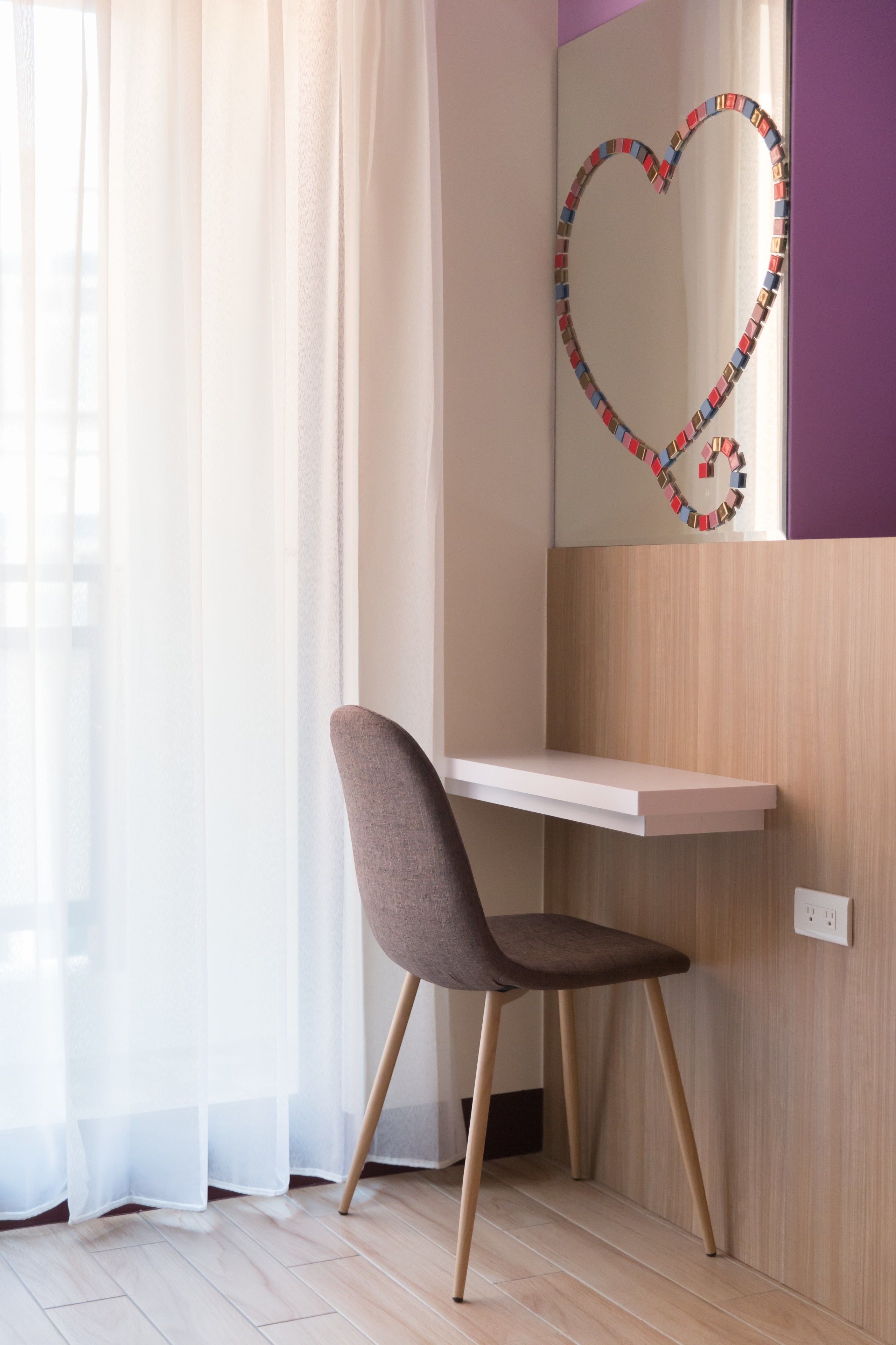 A modern room with a desk, a chair, and a wall-mounted heart-shaped decoration.