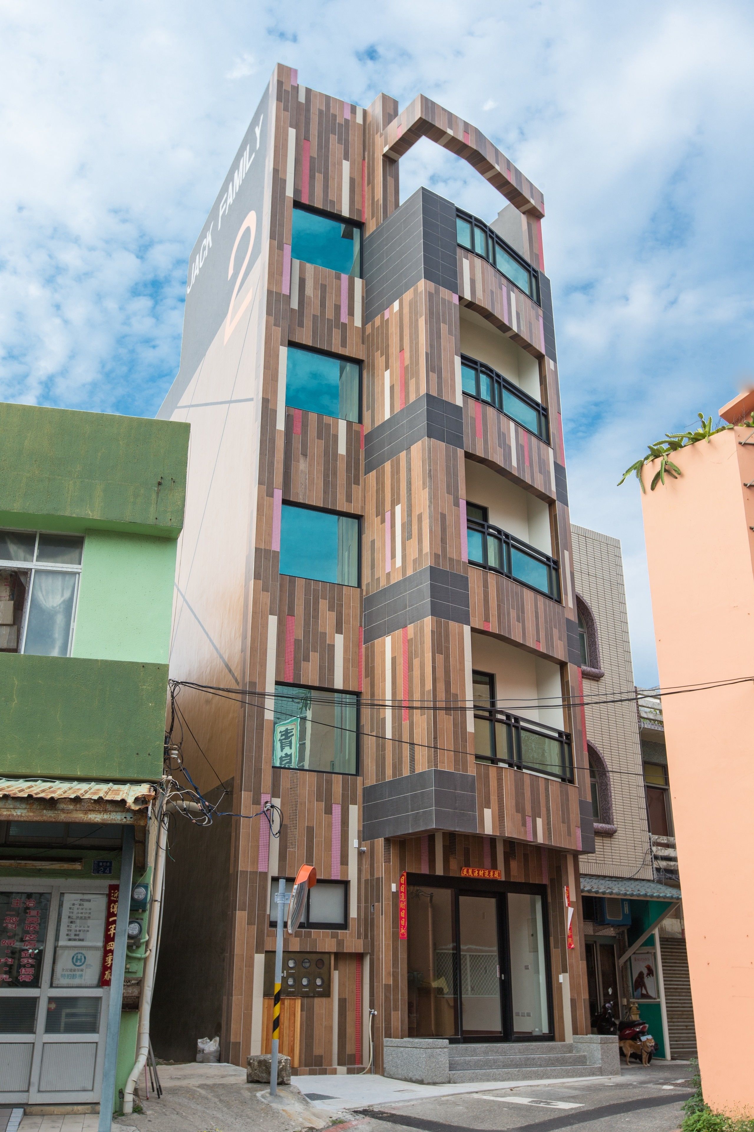 Un immeuble à plusieurs étages, doté d’une architecture moderne, qui combine des panneaux de bois et de grandes fenêtres en verre.
