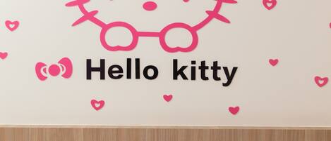 A bedroom with a bed, a pillow, and a wall decal of Hello Kitty.