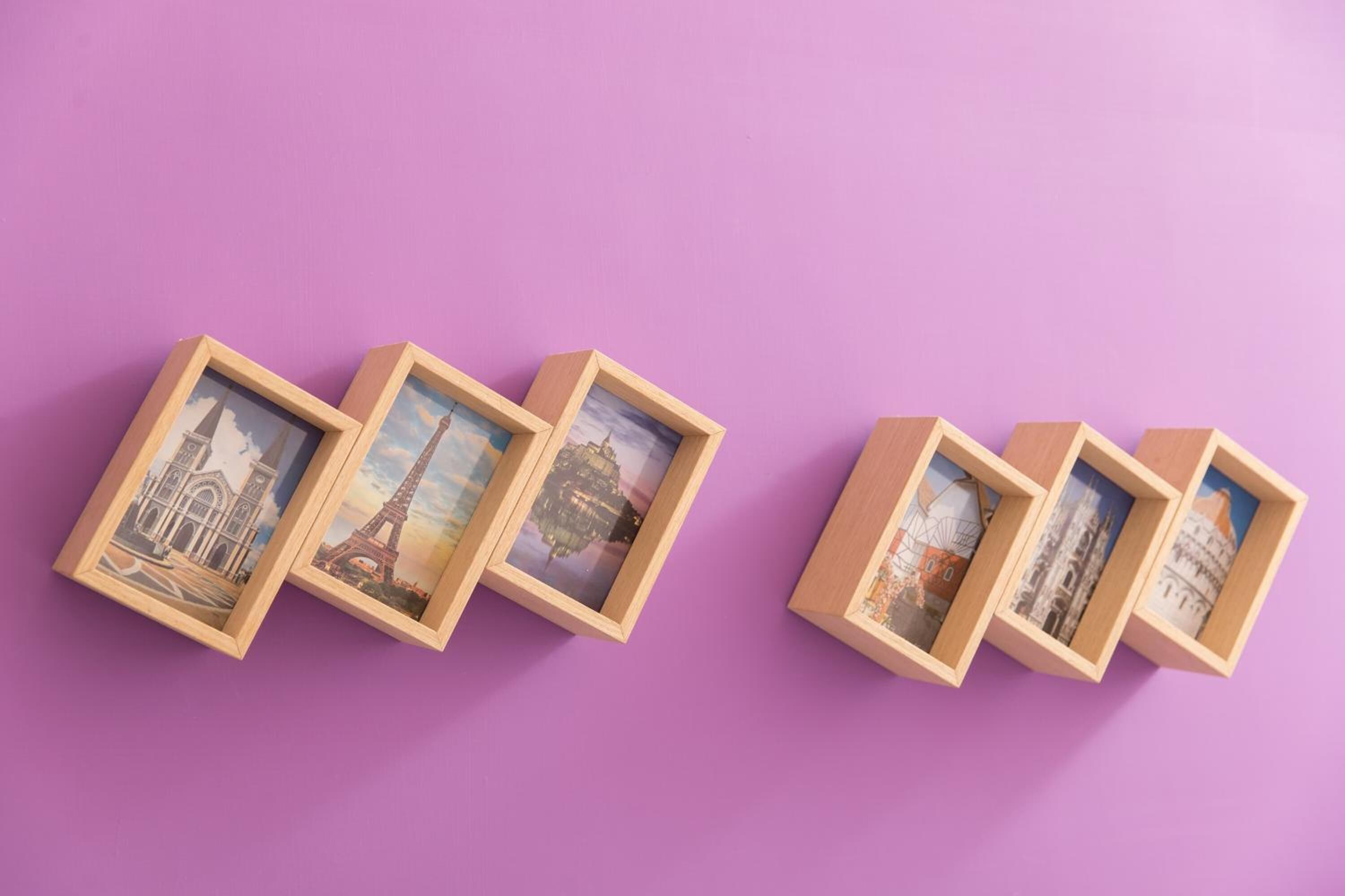 A series of wooden picture frames with travel-themed artwork against a purple background.