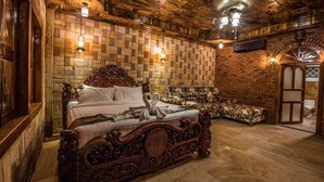 A room with a large ornate bed, a wooden bench, and a brick wall.