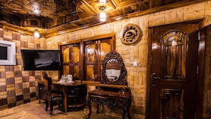 A wooden interior with a TV mounted on the wall, a wooden door, and a mirror with a decorative frame.