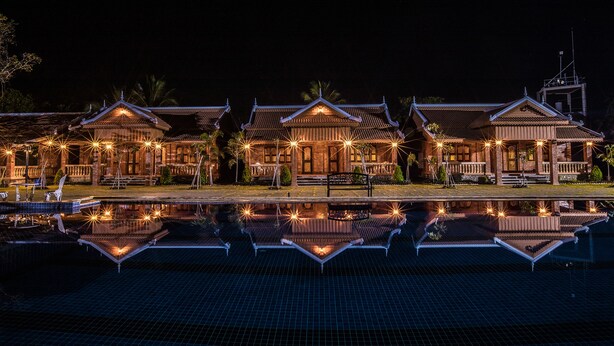 A traditional building with a reflection in a pool, featuring multiple roofs and a central entrance.