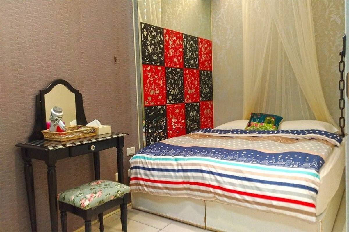 A bedroom with a bed, a bedside table with a mirror, and a decorative headboard.