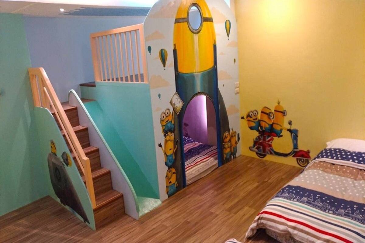 A child's bedroom with a space-themed mural, a wooden staircase, and a bed with a patterned blanket.
