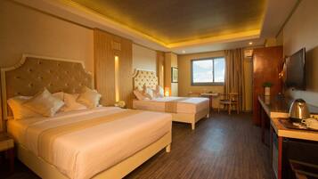 A hotel room with two beds, a desk, a chair, a television, and a window with curtains.