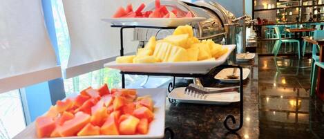 A buffet setup with plates of watermelon, pineapple, and melon.