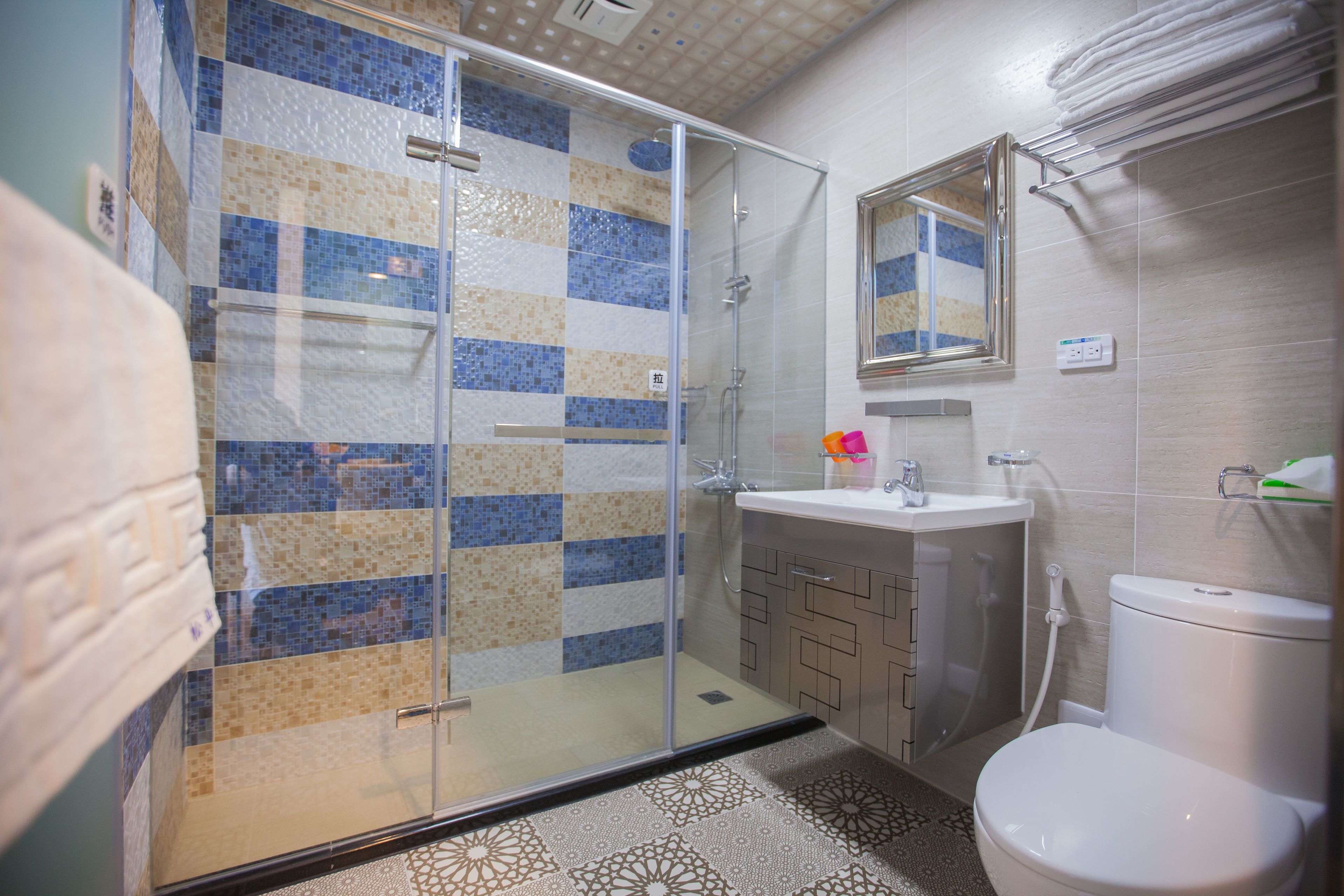 A bathroom with a glass shower enclosure, a sink, and a toilet.