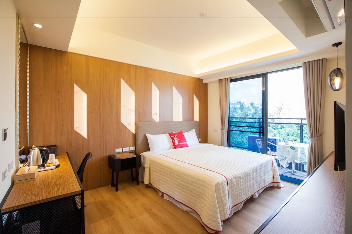 Habitación de hotel moderna con una cama grande, un escritorio y un balcón con vistas.