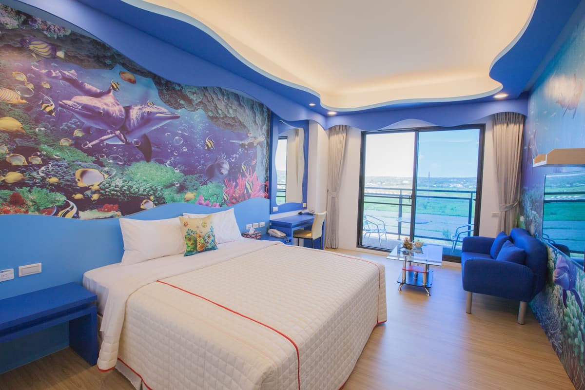 Una habitación con una cama grande, un escritorio y vista al mar.