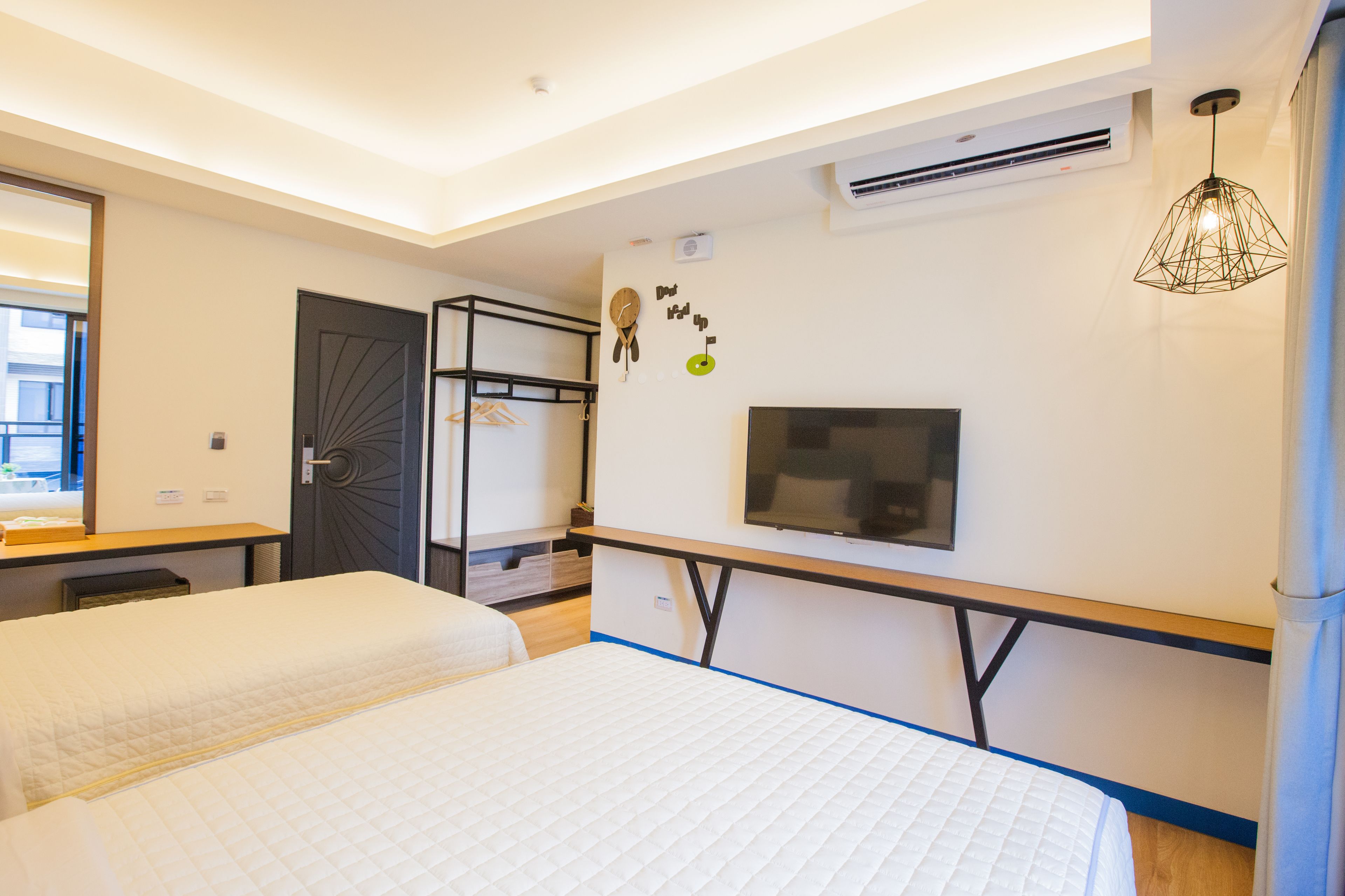A modern hotel room with two beds, a TV, and a wardrobe.