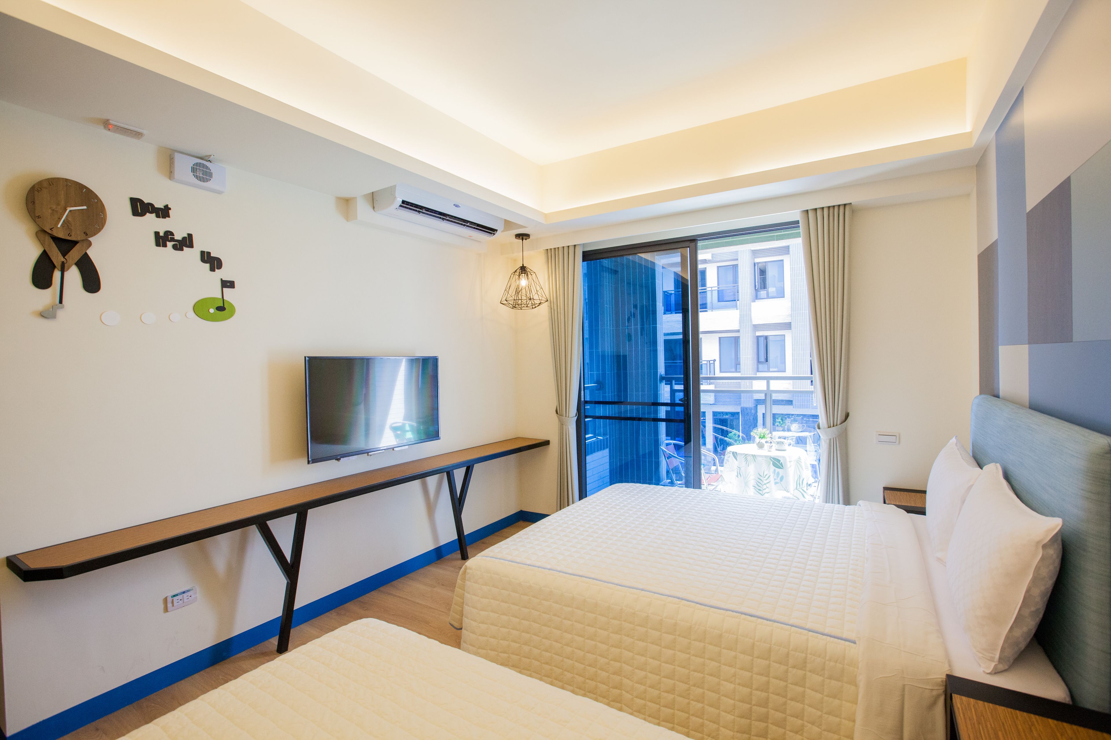 Habitación de hotel con cama, escritorio, televisor y ventana con vistas a edificios.
