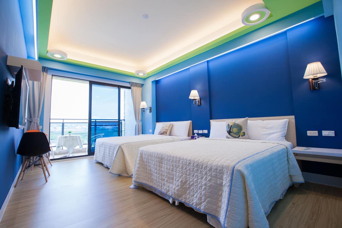 Habitación de hotel con dos camas, un balcón y vista al mar.
