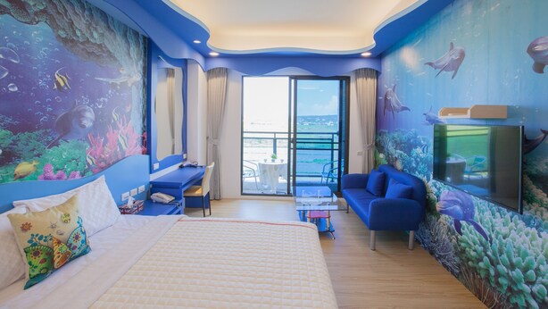 Una habitación con cama, escritorio, sofá y un amplio ventanal.