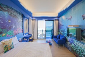 Una habitación con cama, escritorio, sofá y un amplio ventanal.