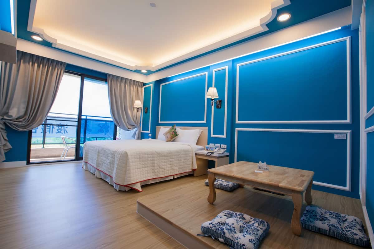 Habitación de hotel con una cama grande, una mesa de madera y vistas al balcón.