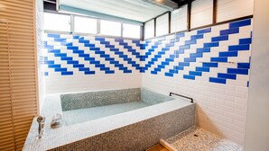 Un baño moderno con una bañera independiente, paredes de azulejos y una ventana que proporciona luz natural.