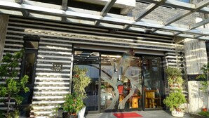 Un edificio moderno con fachada de vidrio, estructura metálica y plantas en macetas.