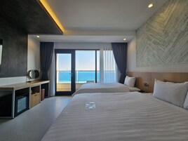 Habitación de hotel con una cama grande, un escritorio con espejo, vistas al mar y un diseño de techo moderno.