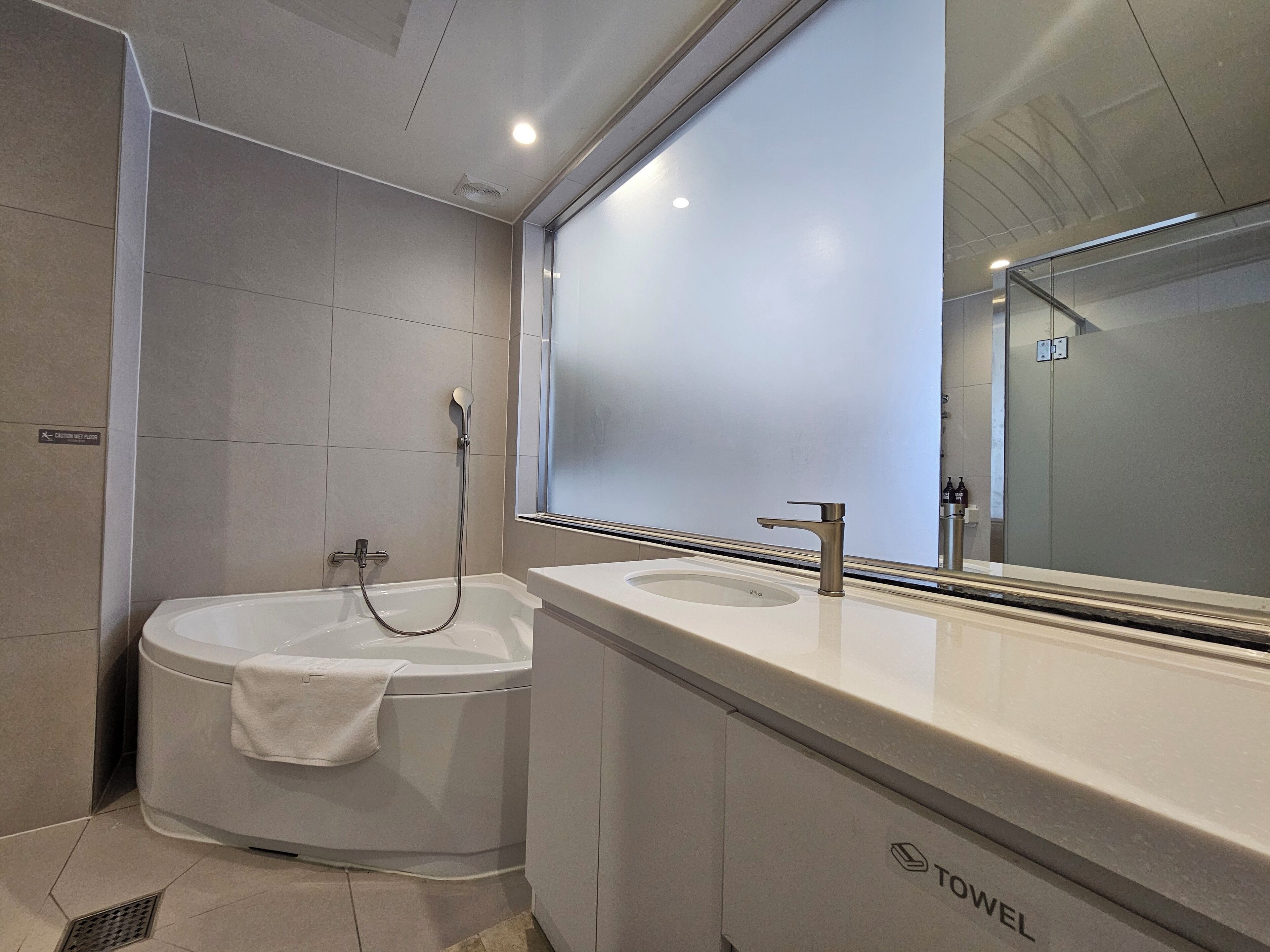Ein modernes Badezimmer mit einer Badewanne, einem Waschbecken und einem großen Spiegel.