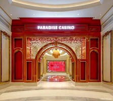 Majestuosa entrada al Casino Paraíso, con una decoración en rojo y dorado, un candelabro y una gran pantalla digital.