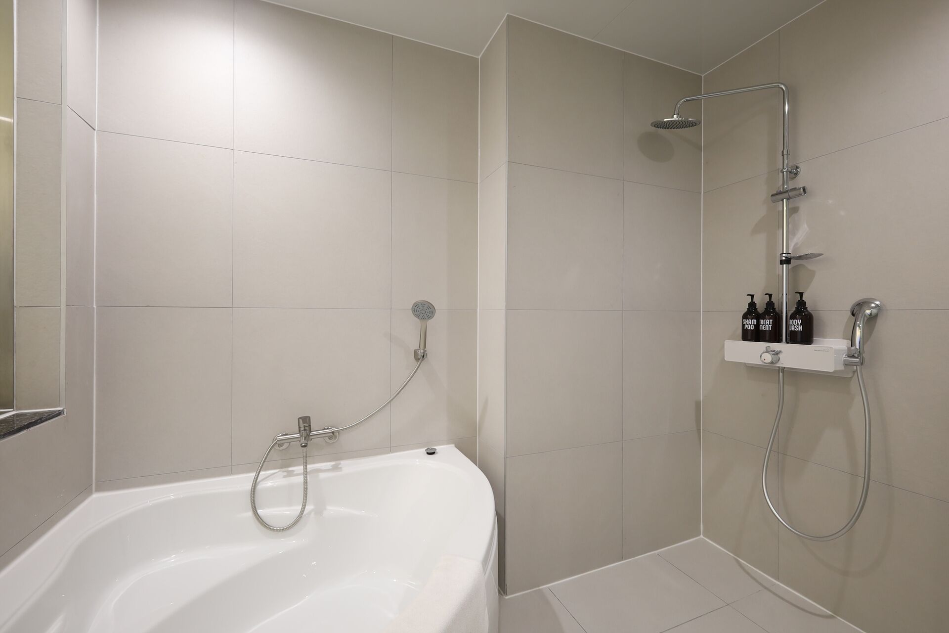 Une salle de bain moderne équipée d’une baignoire, d’une douche et d’une étagère où sont rangés les produits de toilette.