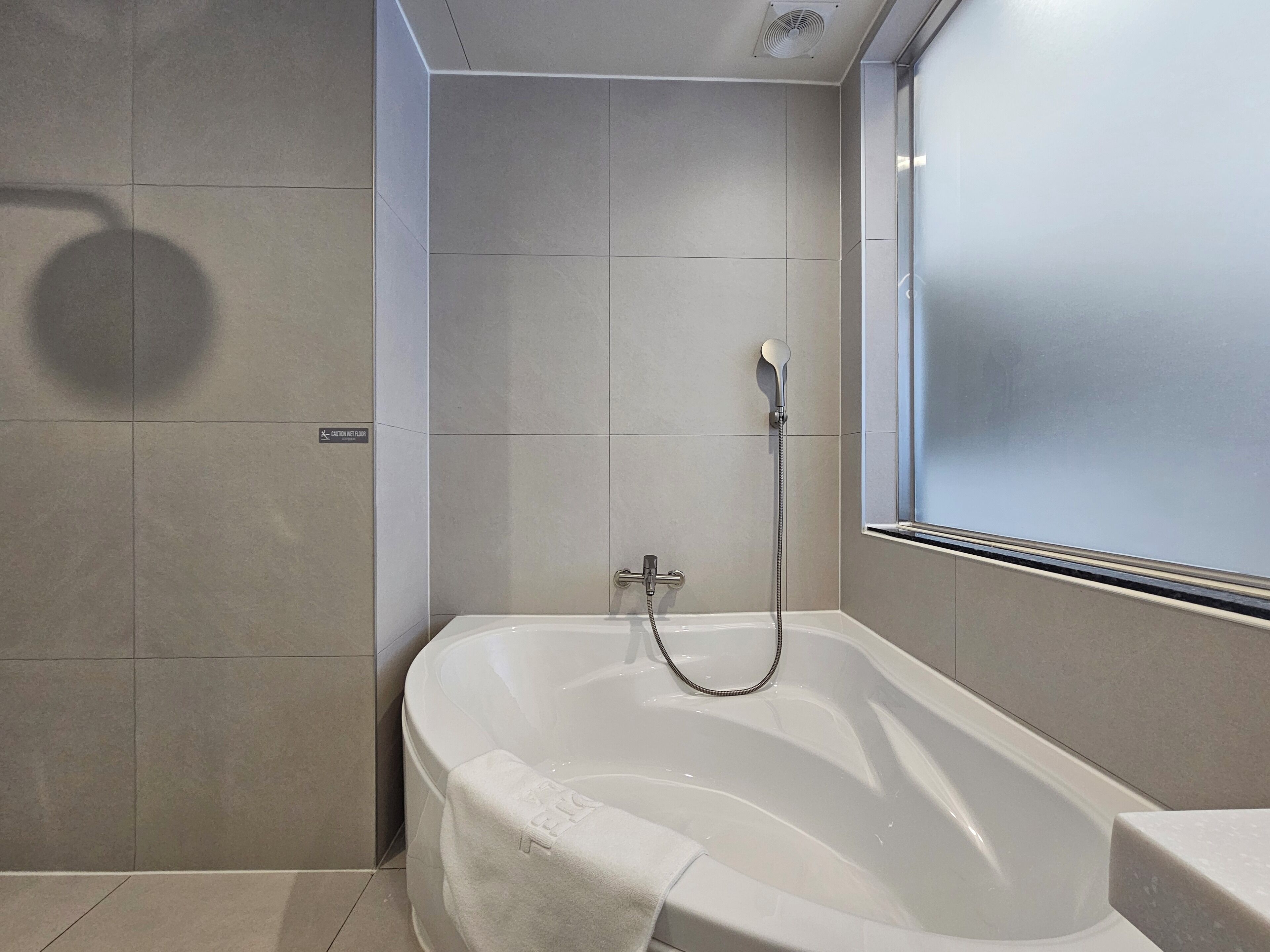 A modern bathroom with a bathtub, a shower, and a window.