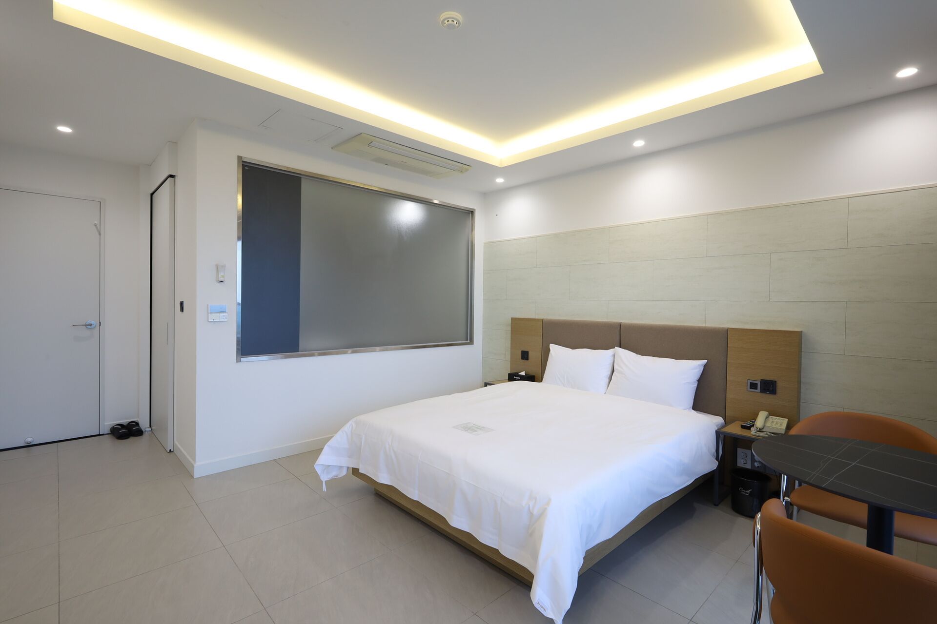 A modern hotel room with a large bed, a desk, and a chair.