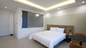 A modern hotel room with a large bed, a desk, and a chair.
