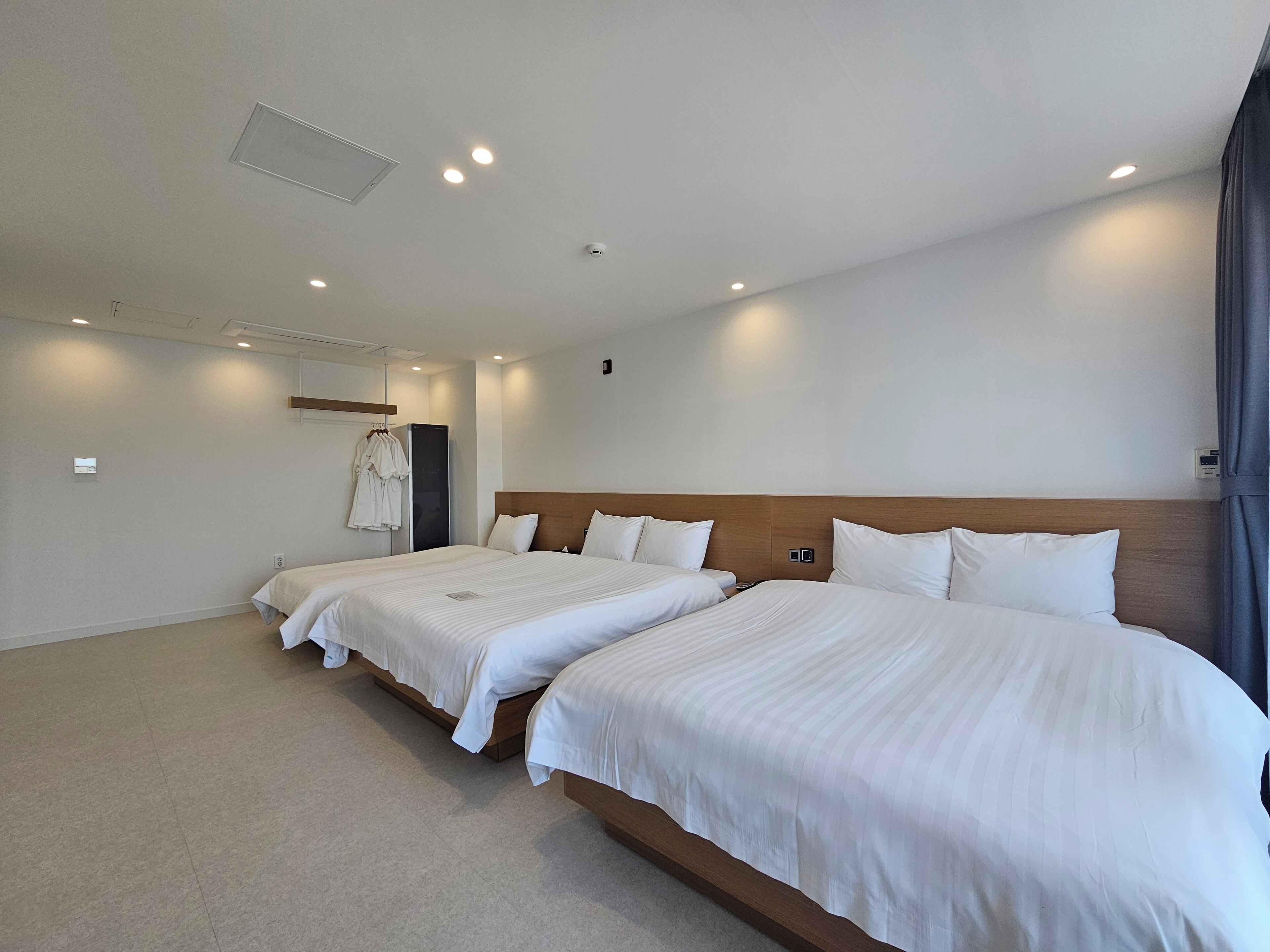 A hotel room with two beds, a wardrobe, a mirror, and a ceiling light.