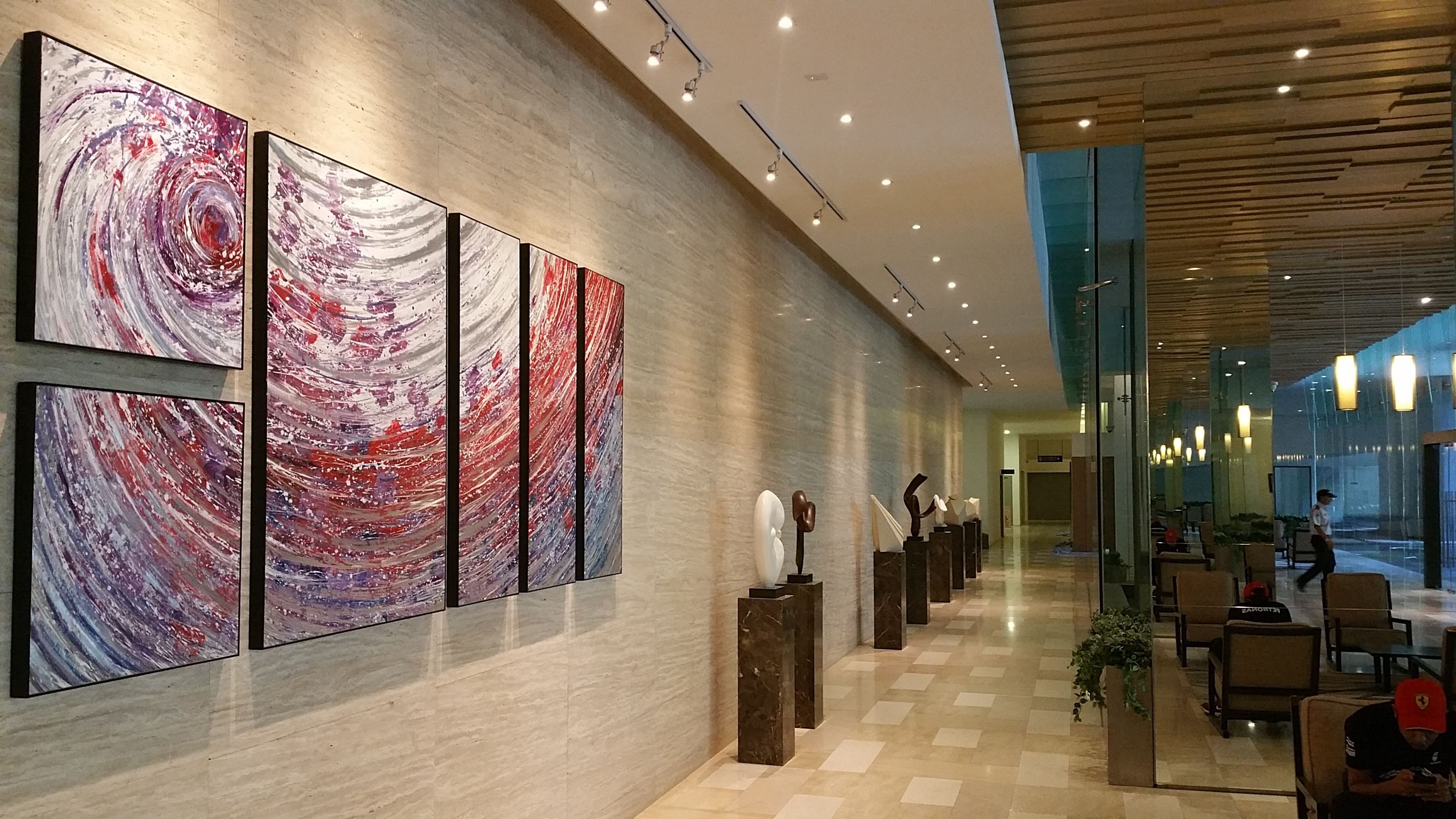 Un hall d’entrée moderne agrémenté d’œuvres d’art abstraites au mur, un comptoir d’enregistrement et un espace détente avec des tables et des chaises.